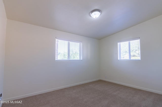 carpeted empty room featuring vaulted ceiling