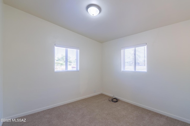 carpeted empty room featuring plenty of natural light and vaulted ceiling