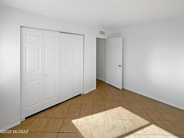 unfurnished bedroom featuring light tile patterned flooring and a closet