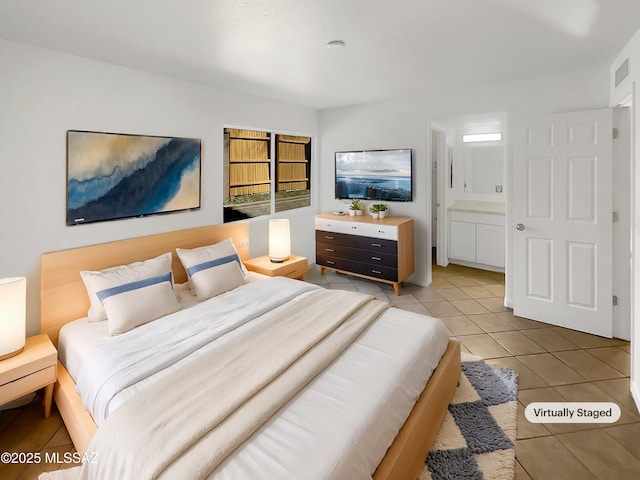 bedroom featuring ensuite bathroom and light tile patterned flooring