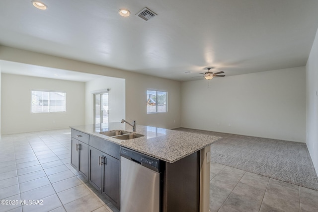 kitchen featuring light stone countertops, dishwasher, sink, a kitchen island with sink, and light tile patterned floors