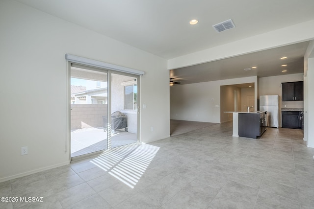 unfurnished living room with ceiling fan, sink, and light tile patterned floors