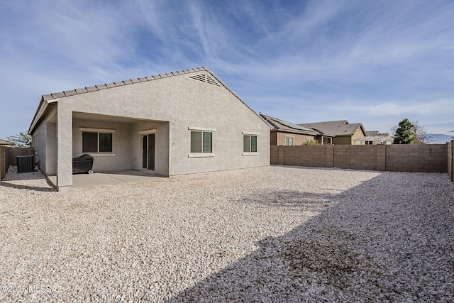 rear view of property featuring a patio, cooling unit, stucco siding, and a fenced backyard