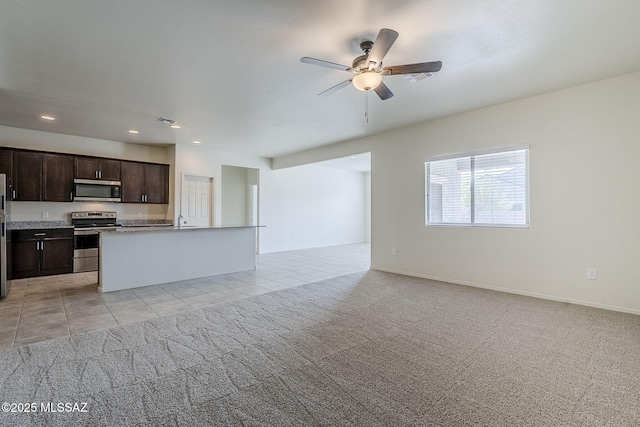 kitchen with a kitchen island with sink, ceiling fan, dark brown cabinets, light colored carpet, and stainless steel appliances