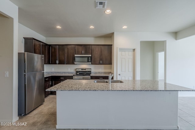 kitchen featuring dark brown cabinets, visible vents, light stone counters, a sink, and stainless steel appliances