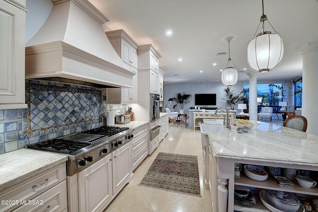 kitchen with pendant lighting, a large island with sink, custom exhaust hood, and ornate columns