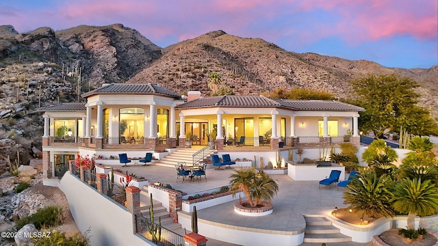 back house at dusk with a mountain view, a patio area, and an outdoor kitchen