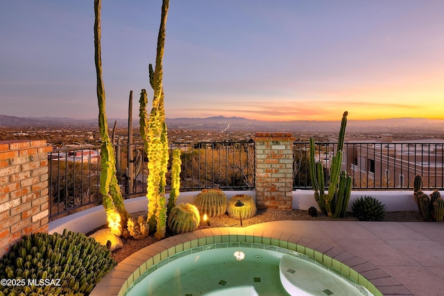 pool at dusk featuring an in ground hot tub and a mountain view