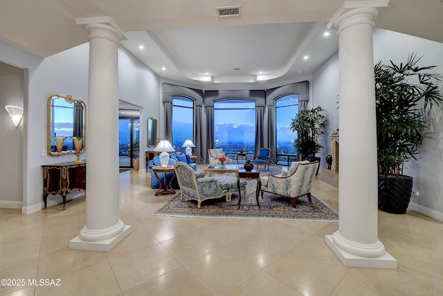 living room featuring light tile patterned floors, a tray ceiling, and decorative columns