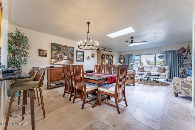 dining room featuring ceiling fan with notable chandelier and a skylight