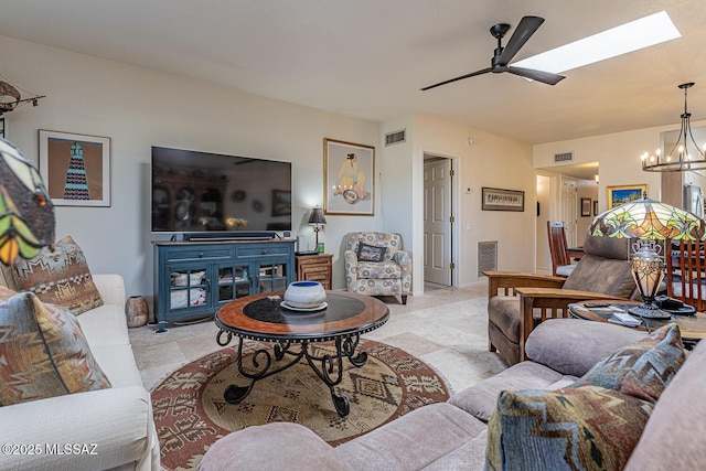 living room with visible vents, a skylight, and ceiling fan with notable chandelier