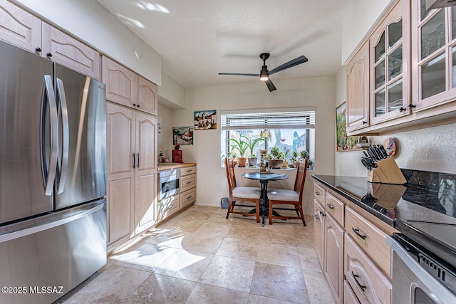 kitchen with glass insert cabinets, baseboards, ceiling fan, dark stone countertops, and appliances with stainless steel finishes