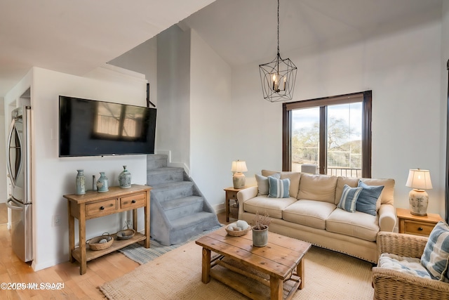 living room featuring light wood-style floors, a chandelier, and stairs