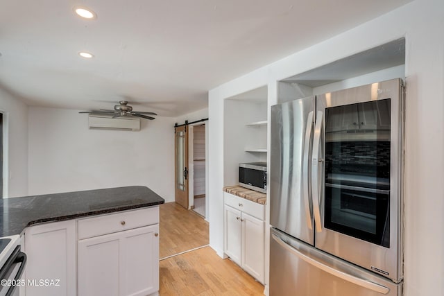 kitchen with open shelves, stainless steel appliances, a wall mounted AC, a barn door, and white cabinetry