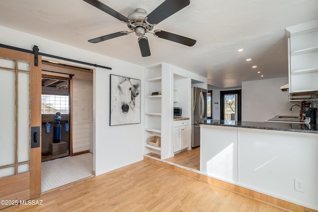 kitchen featuring appliances with stainless steel finishes, white cabinetry, light wood-style flooring, and open shelves