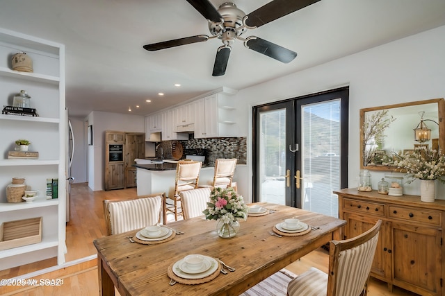 dining area with light wood finished floors, a ceiling fan, and french doors