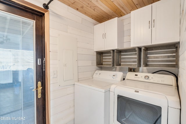 washroom with wood ceiling, cabinet space, wood walls, and washer and clothes dryer