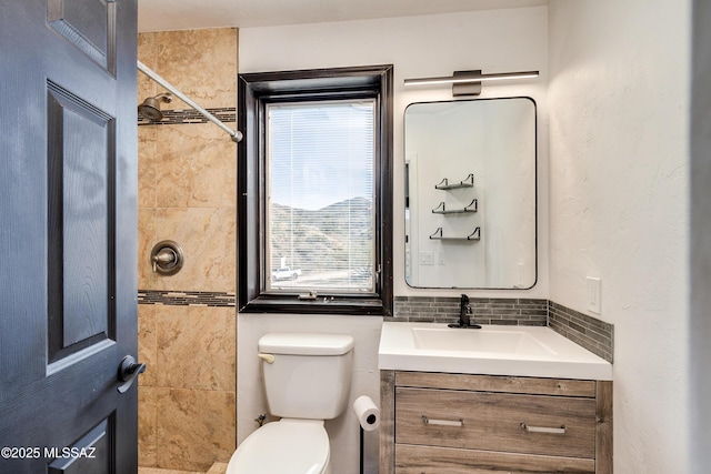 bathroom with tasteful backsplash, a tile shower, vanity, and toilet