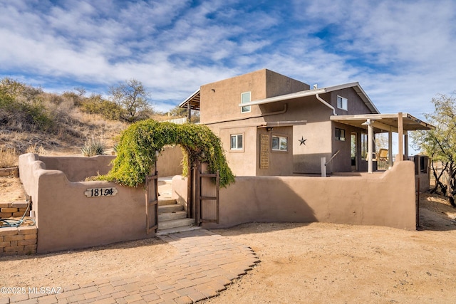 view of side of home with a fenced front yard, a gate, and stucco siding