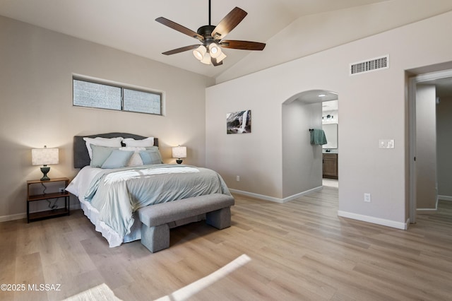 bedroom featuring ceiling fan, vaulted ceiling, ensuite bath, and light hardwood / wood-style flooring