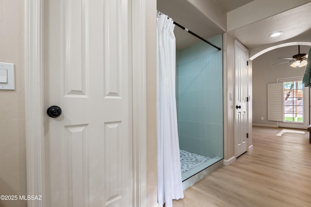 bathroom with wood-type flooring, walk in shower, and ceiling fan