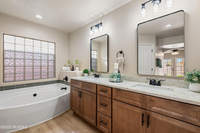 bathroom with vanity, french doors, hardwood / wood-style flooring, ceiling fan, and a washtub