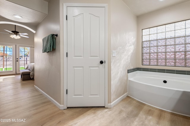 bathroom with hardwood / wood-style floors, plenty of natural light, a bathtub, and ceiling fan