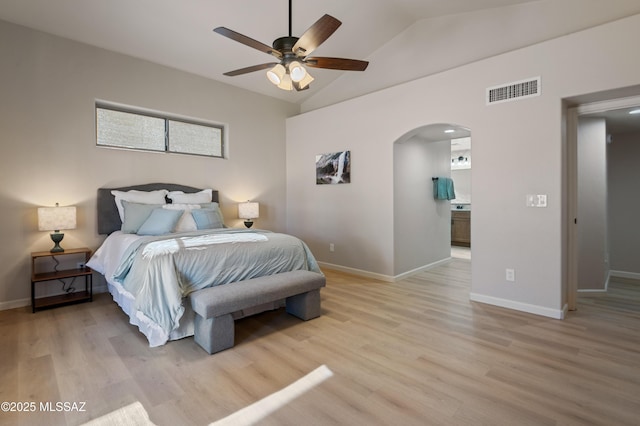 bedroom with ceiling fan, light wood-type flooring, connected bathroom, and lofted ceiling