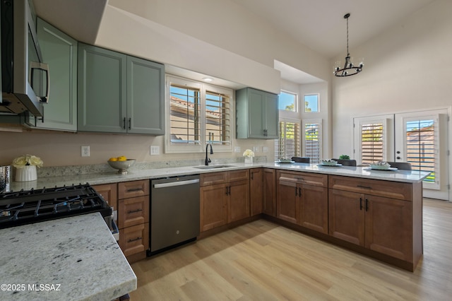 kitchen with decorative light fixtures, light stone countertops, sink, and appliances with stainless steel finishes