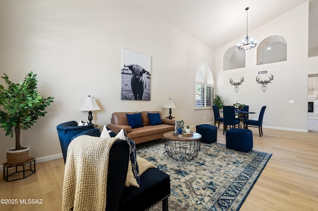 living room featuring light wood-type flooring, high vaulted ceiling, and an inviting chandelier