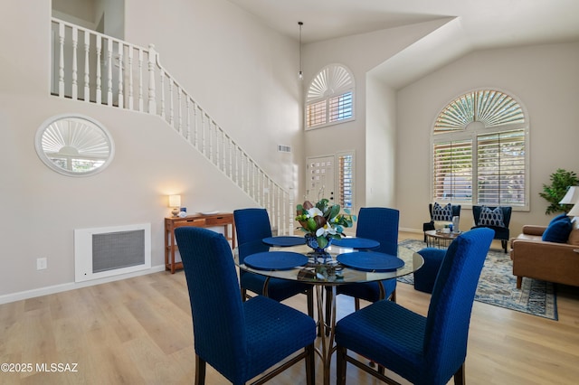 dining room with light wood-type flooring and a high ceiling