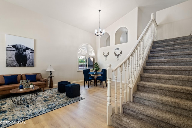 living room featuring wood-type flooring, a high ceiling, and an inviting chandelier