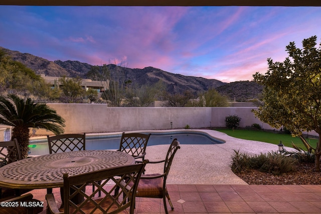 pool at dusk with a mountain view and a patio