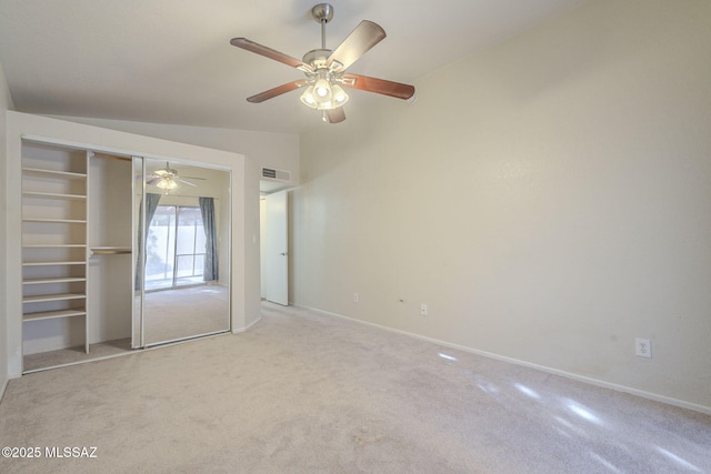 unfurnished bedroom with lofted ceiling, a closet, visible vents, carpet flooring, and baseboards