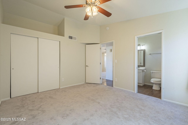 unfurnished bedroom with connected bathroom, carpet flooring, visible vents, vaulted ceiling, and a closet