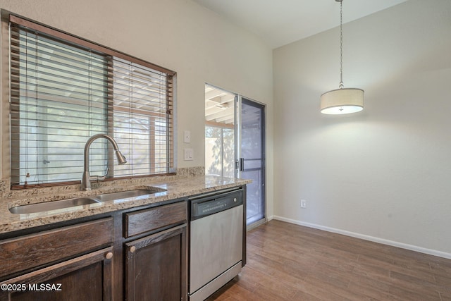 kitchen featuring light stone countertops, sink, dishwasher, and decorative light fixtures