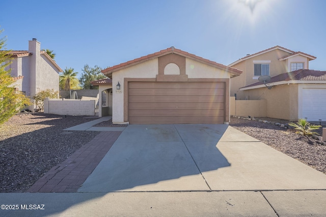 view of front of house with a tile roof, stucco siding, fence, a garage, and driveway