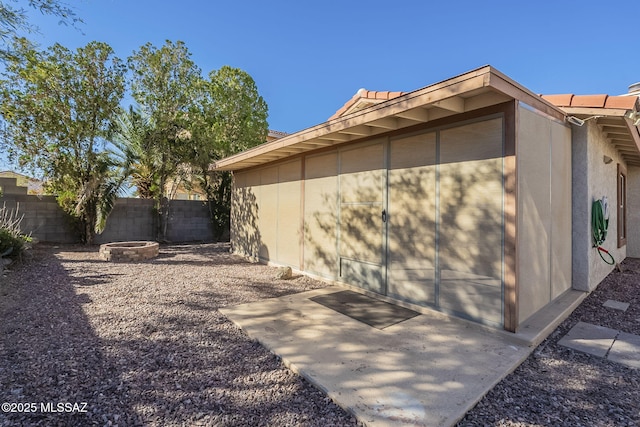 view of side of home with an outdoor fire pit, a patio area, fence, and stucco siding