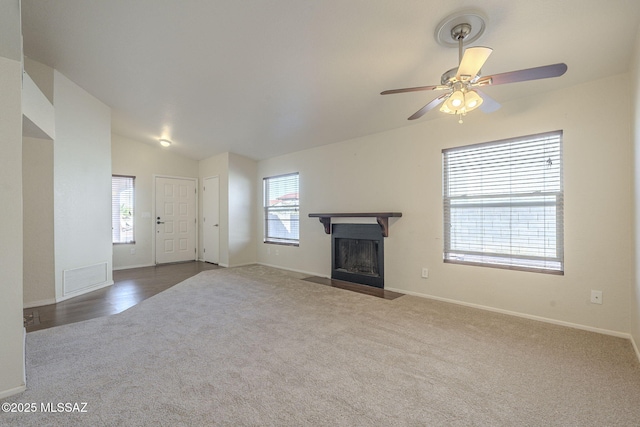 unfurnished living room with lofted ceiling, carpet, a fireplace with flush hearth, and visible vents