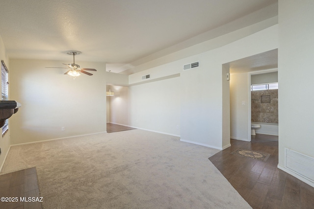 unfurnished living room featuring vaulted ceiling, visible vents, and baseboards