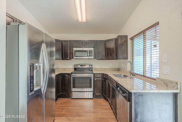 kitchen with dark brown cabinetry, appliances with stainless steel finishes, a textured ceiling, light wood-type flooring, and a sink