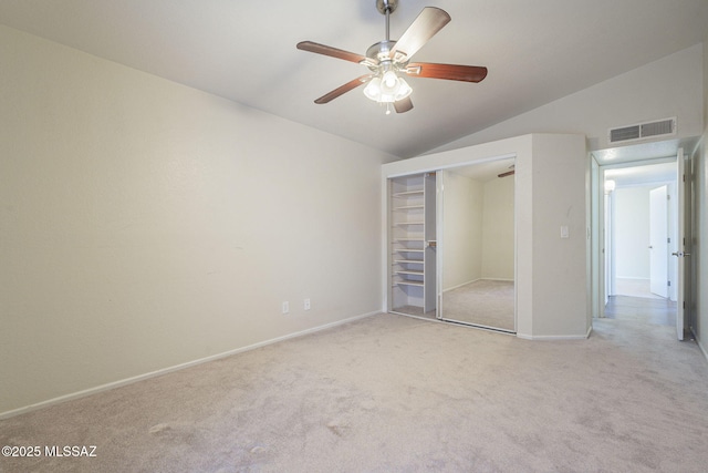 unfurnished bedroom featuring light carpet, baseboards, visible vents, lofted ceiling, and a closet