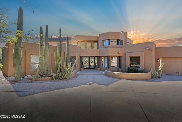 adobe home with stucco siding and a garage