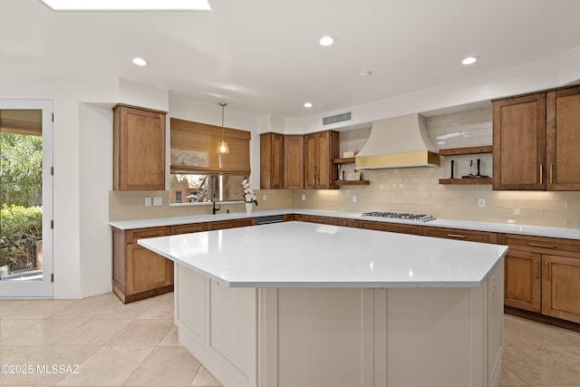 kitchen featuring open shelves, custom exhaust hood, brown cabinetry, and visible vents