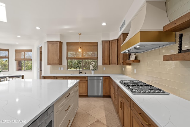 kitchen with visible vents, custom exhaust hood, a sink, decorative backsplash, and stainless steel appliances