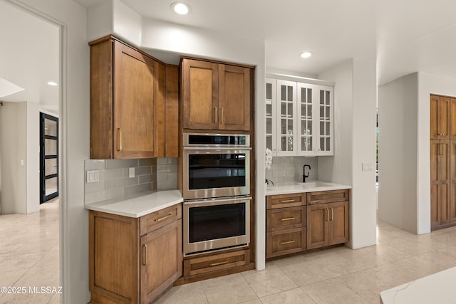 6872 E Desert Wind Ct, Tucson, AZ 85750 - kitchen with stainless steel double oven, decorative backsplash, brown cabinets, light countertops, and recessed lighting