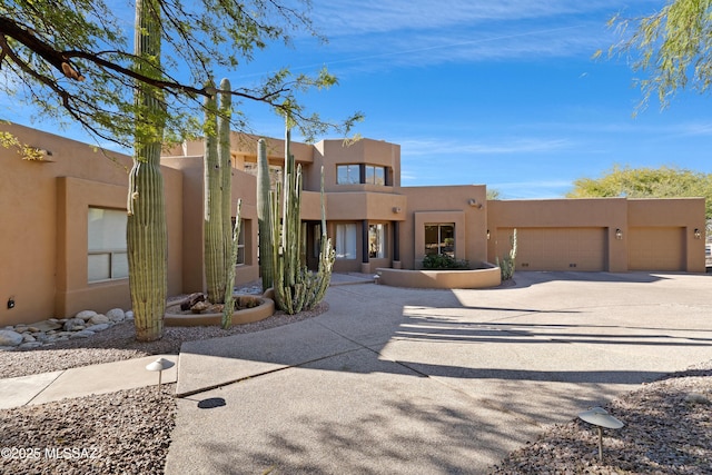 southwest-style home featuring concrete driveway, a garage, and stucco siding