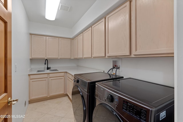 clothes washing area with visible vents, a sink, cabinet space, separate washer and dryer, and light tile patterned floors