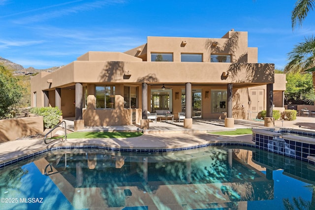 back of property featuring an in ground hot tub, a patio area, an outdoor pool, and stucco siding