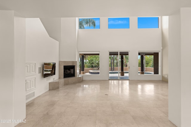 6872 E Desert Wind Ct, Tucson, AZ 85750 - unfurnished living room with a high ceiling, healthy amount of natural light, a fireplace, and tile patterned flooring